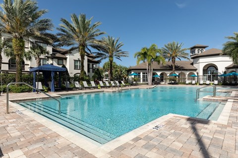 a large swimming pool with palm trees in front of a building