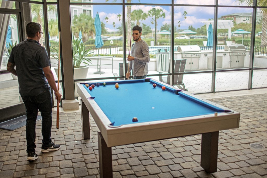 two men playing pool in the screened outdoor pavilion