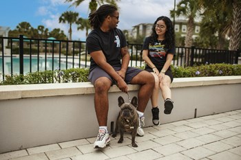 Ariel-3-22-Lifestyle-petfriendly two people sitting on low wall by pool with dog on a leash - Photo Gallery 2