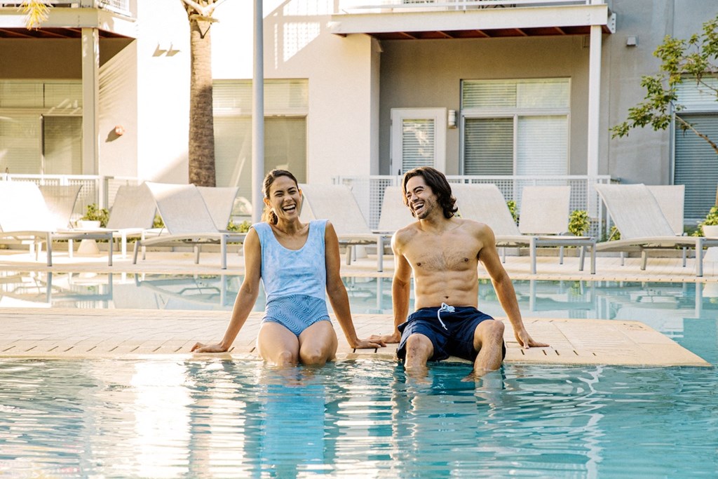 Two people sitting on the edge of the pool with their legs in the water in Lake Nona, Orlando, FL 32827