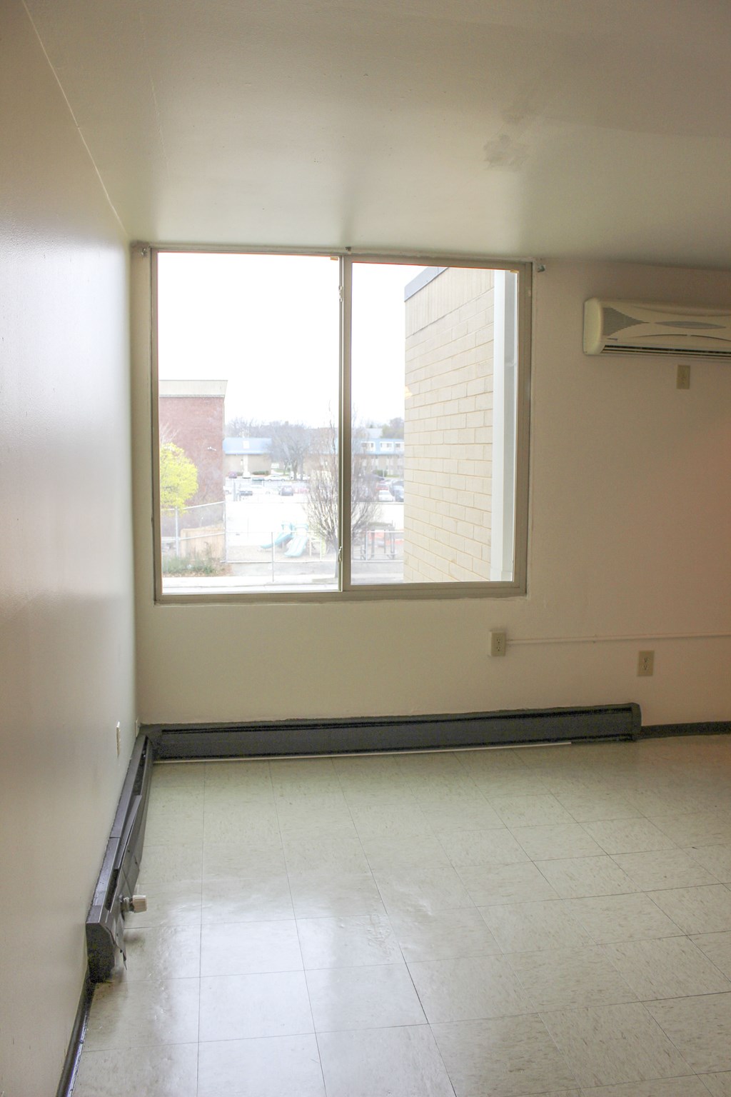 A room with a window and a wall-mounted air conditioner.