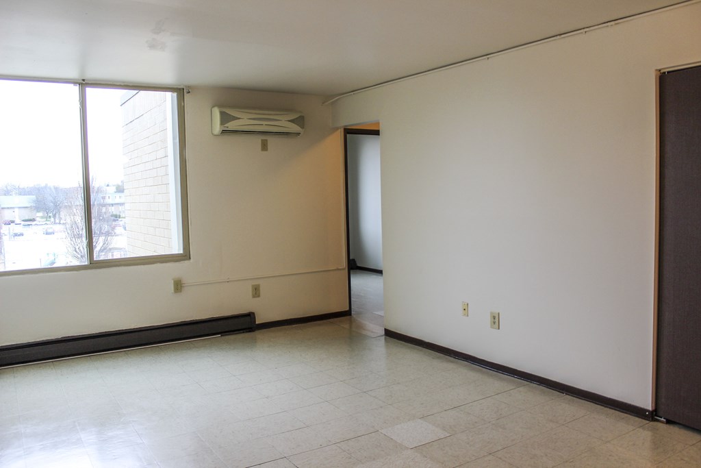 A room with a window, a door, and a wall-mounted air conditioner.