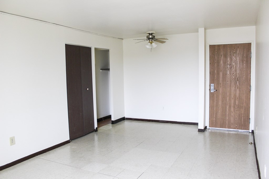 A room with a ceiling fan and three doors.