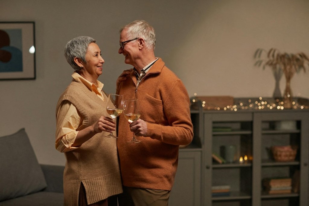 an older couple dancing and holding wine glasses