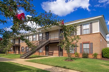 brick apartment building with green grass, sidewalk, and crepe myrtle trees at The Mills at 601, Prattville, 36066 - Photo Gallery 12