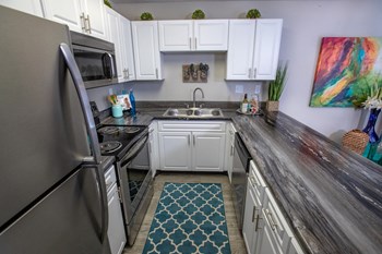 galley kitchen with white cabinets and stainless steel appliances and granite style counters at The Mills at 601, Prattville, AL, 36066 - Photo Gallery 14
