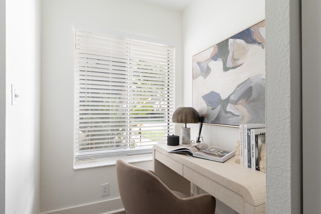 A brown chair is in front of a desk with a lamp and books on it.