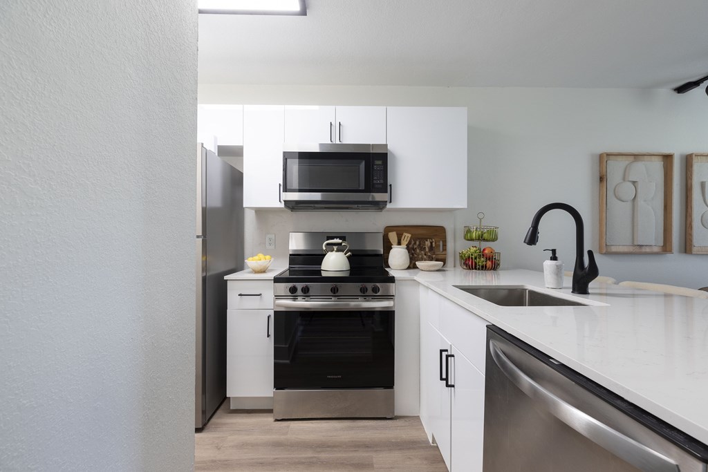 A modern kitchen with white cabinets and stainless steel appliances.