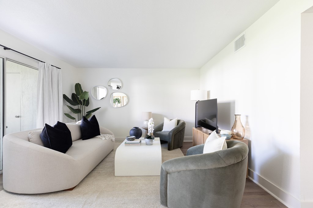A living room with a white couch, grey armchair, and a white coffee table.