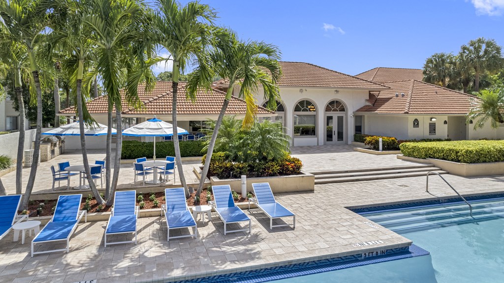 A pool area with sun loungers and a building in the background.