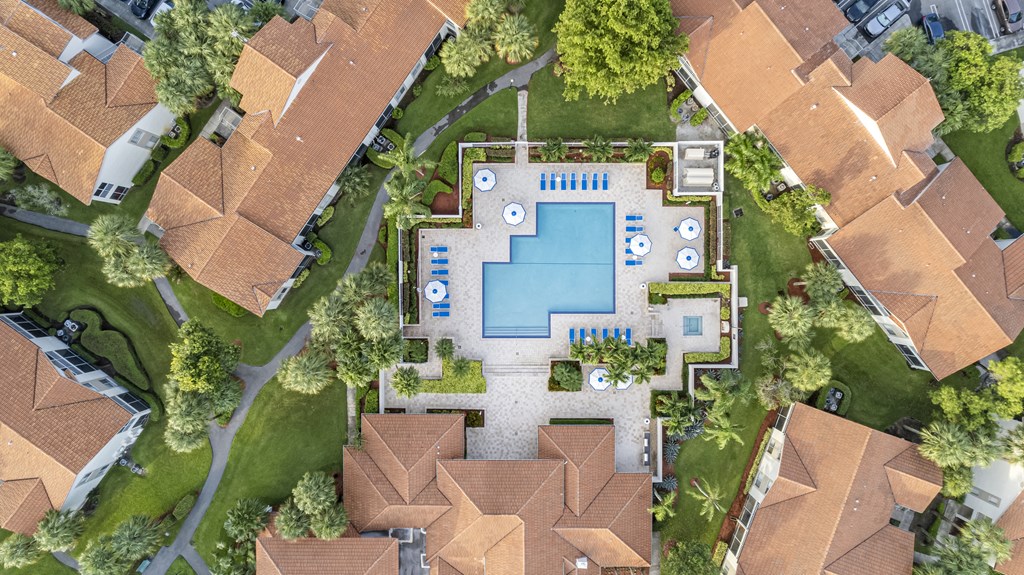 A bird's eye view of a residential area with a swimming pool and a small garden.