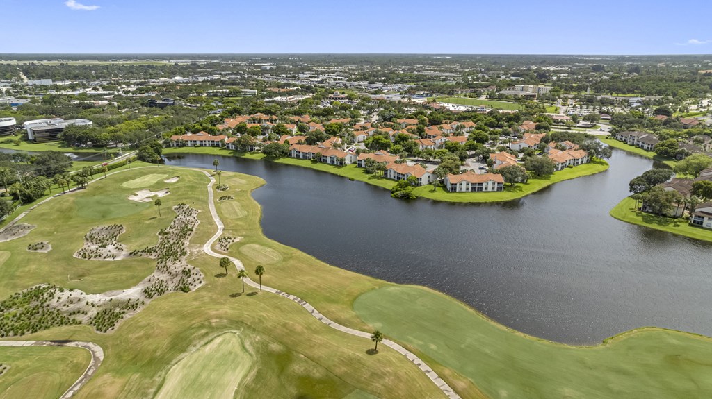 A golf course with a lake and houses in the background.
