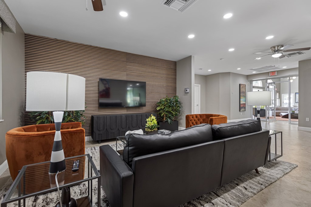A modern living room with a black couch and a television on the wall.