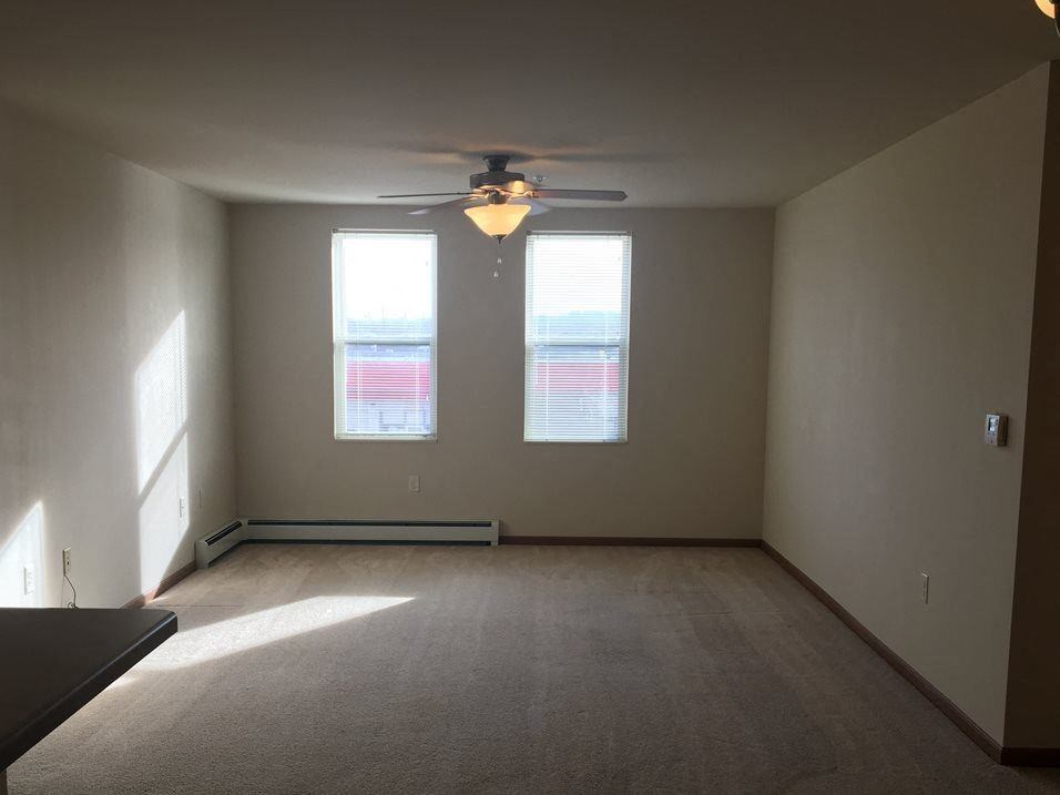 a living room with a ceiling fan and two windows