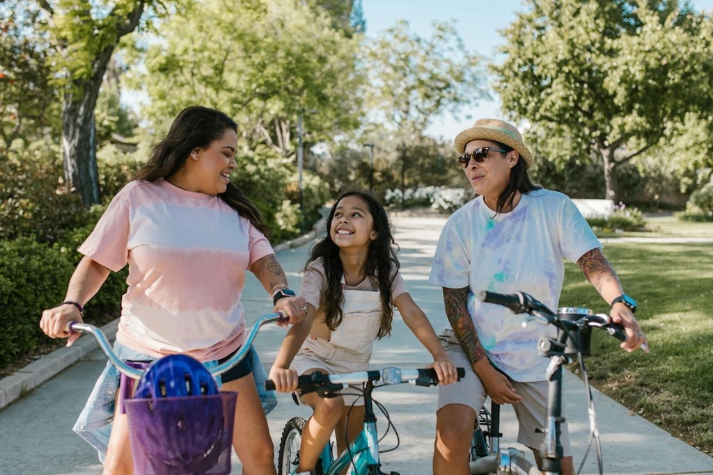 a mother, child, and father riding bikes down a street together