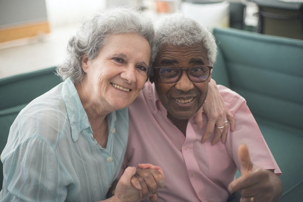 older couple hugging and smiling inside apartment