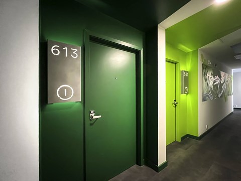 residential hall with bright green doors, mural, large door numbers, and smart locks