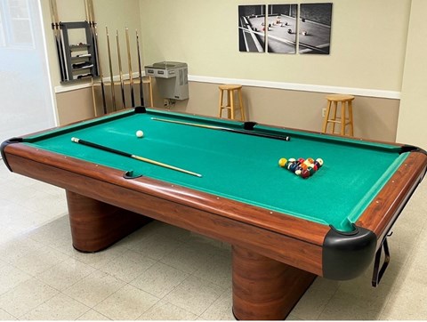 pool table with plenty of cues, bar stools, and water fountain