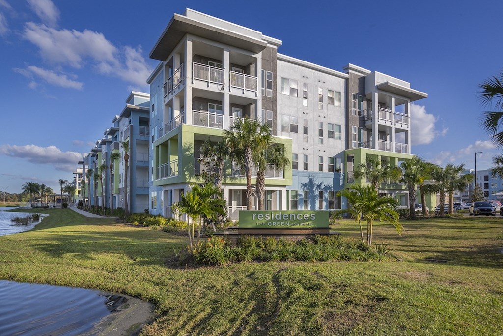 monument sign on lush green lawn by pond at Residences at The Green Apartments in Lakewood Ranch, Bradenton, FL