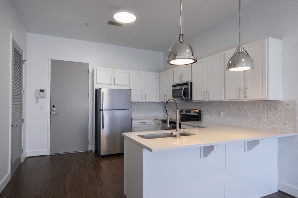 Kitchen with stainless steel appliances, wood-style floors, and pendant lights at Rise Lakeview Apartments in Birmingham, AL