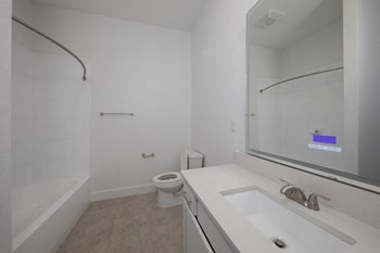 Spacious bathroom with smart mirror, tub, shower, toilet, and sink vanity at Rise Lakeview at Rise Lakeview Apartments in Birmingham, AL - Photo Gallery 10