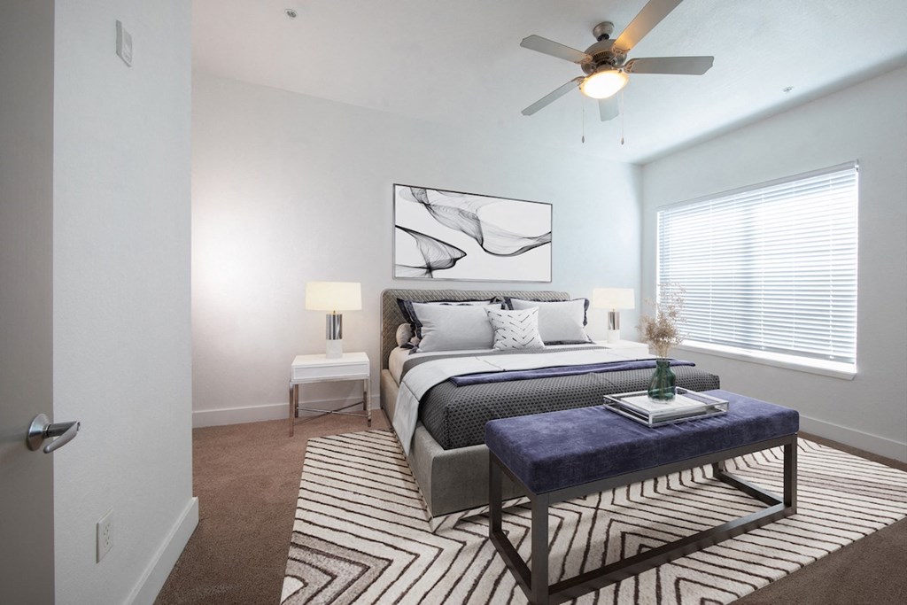 Spacious carpeted bedroom with large window, ceiling fan, and model furnishings at Rise Lakeview Apartments in Birmingham, AL