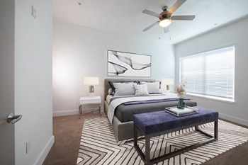Spacious carpeted bedroom with large window, ceiling fan, and model furnishings at Rise Lakeview Apartments in Birmingham, AL - Photo Gallery 11