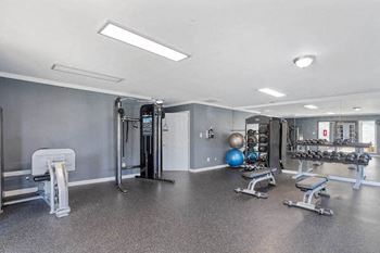 large fitness center with mirrored wall, free weights, balls, and benches