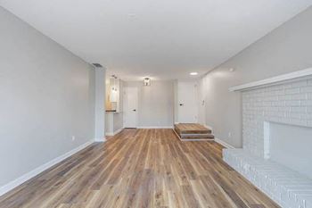 a living room with a beautiful wood-style flooring and a white brick fireplace