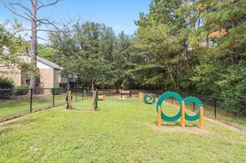 a large fenced dog park with an agility course at The Onyx Hoover Apartments