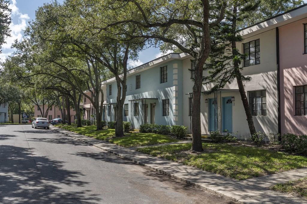 Pastel blue, white, and pink apartment homes with mature trees and neat sidewalks at Terraces at Clearwater Beach, Clearwater, 33756