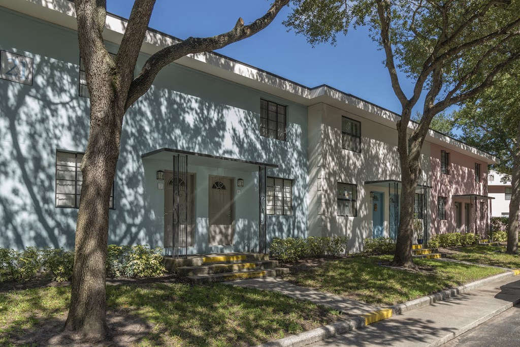 Pastel blue, white, and pink apartment homes with mature trees and neat sidewalks at Terraces at Clearwater Beach, Clearwater, FL