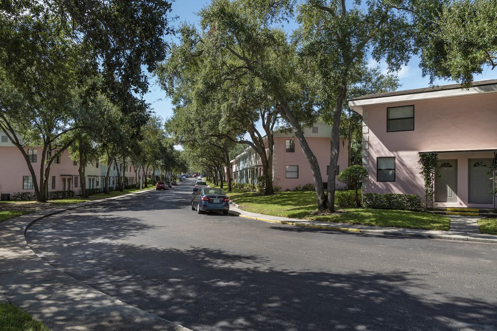 Tree-lined street with pastel colored apartment buildings at Terraces at Clearwater Beach, Clearwater, FL, 33756