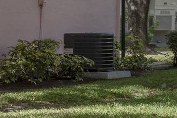 An air conditioning unit on a platform in the grass next to a residential building at Terraces at Clearwater Beach