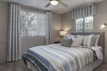 large windows covered by verticle blinds in a bedroom with model furniture at Terraces at Clearwater Beach