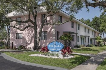 the monument sign and residential buildings surrounded by lush, mature trees and plants