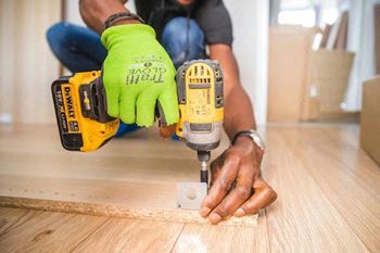 a man working on a wood-style floor with a drill