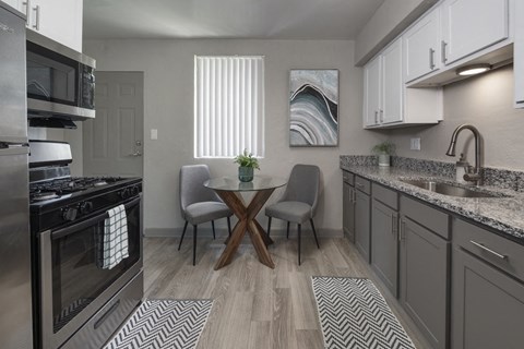 an open kitchen and dining room with stainless steel appliances and a table and chairs