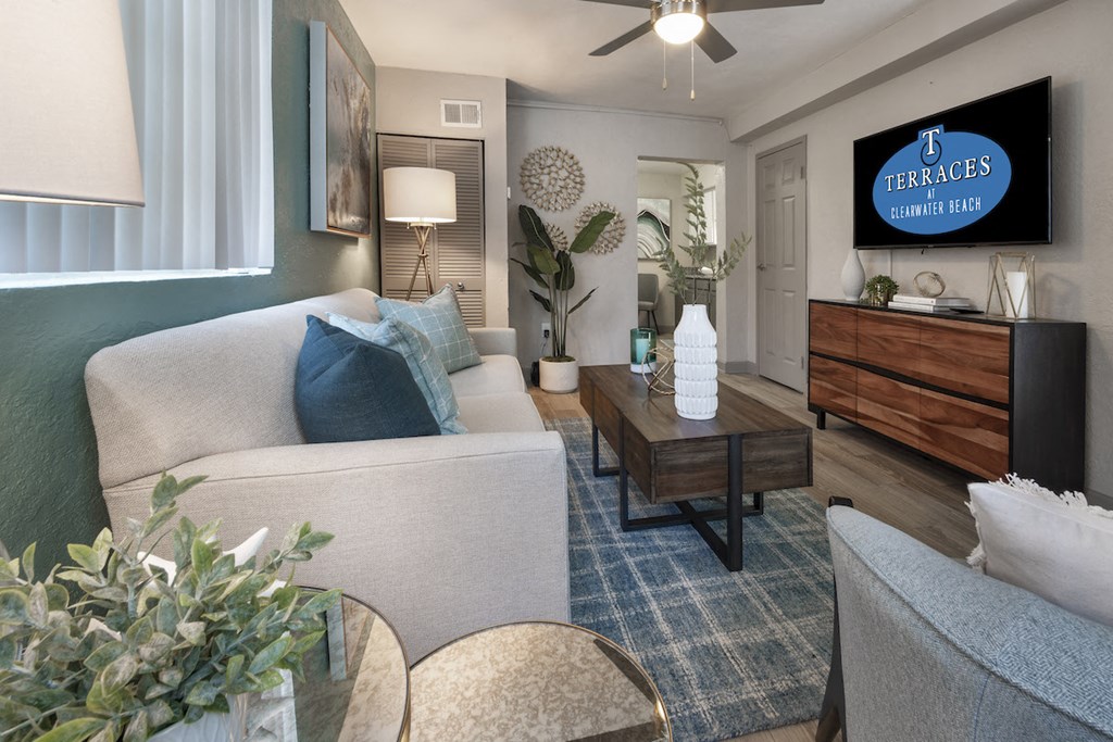 Living room with fan, large windows, model décor, and wood-style floors at Terraces at Clearwater Beach, Florida, 33756