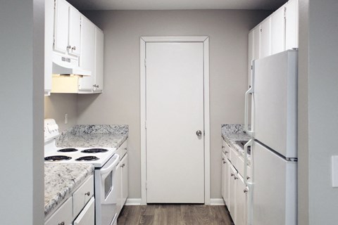a kitchen with white appliances and white cabinets and a white door