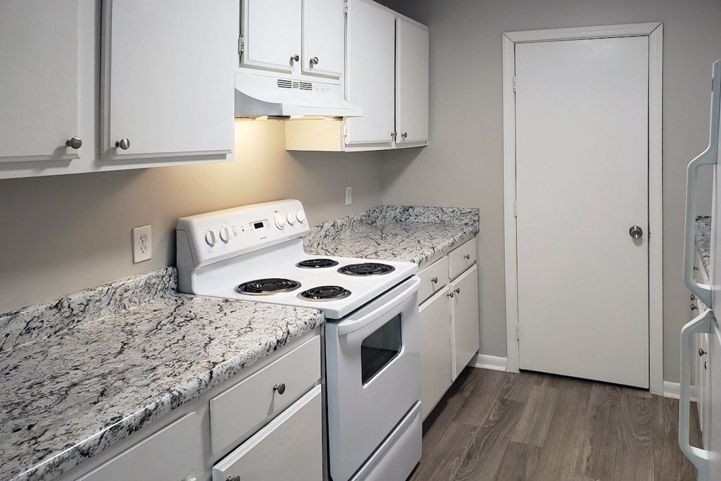 The Bluffs Kitchen with white stove, white cabinets and wood-style flooring at The Bluffs