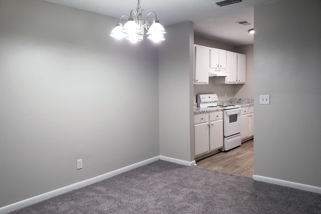 Apartment living room with a chandelier and a kitchen in the background at The Bluffs in Jasper, Alabama