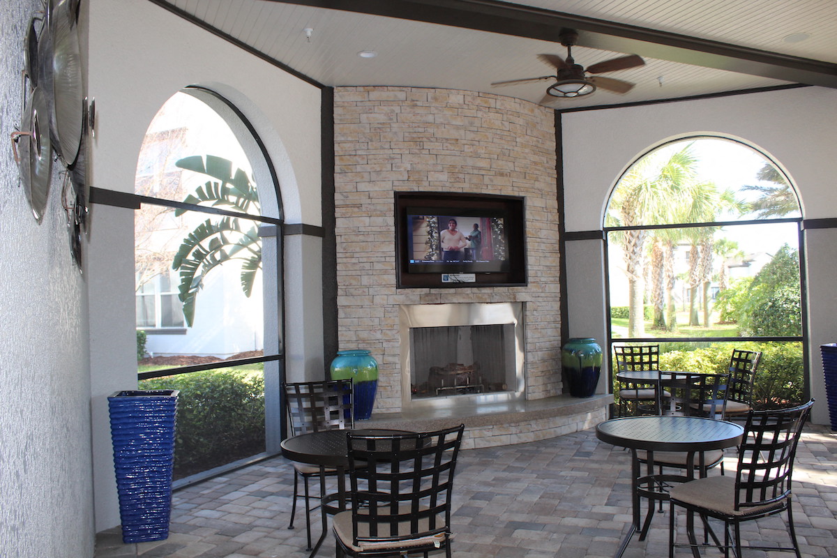 Outdoor lounge with fireplace, TV, and tables and chairs in Orlando, FL 32827