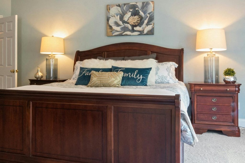 a bedroom with a large bed, plush bedding, and bedside tables with decor and lamps