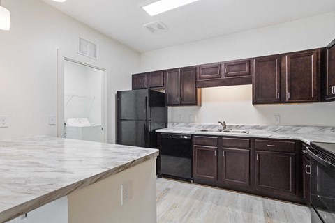 an empty kitchen with black appliances and marble counter tops