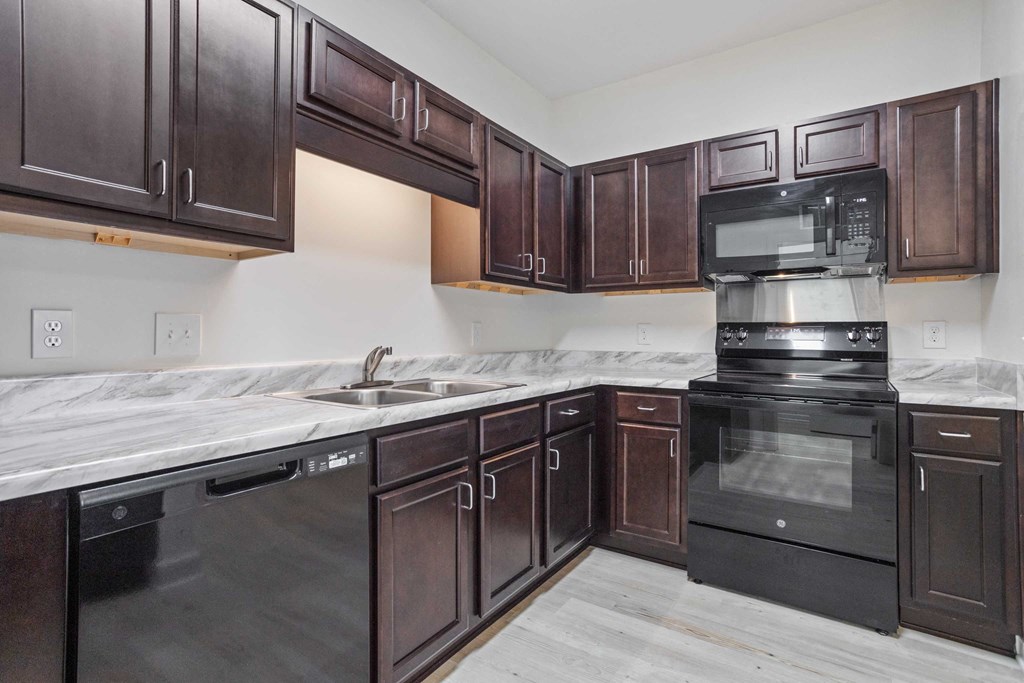 a kitchen with dark wood cabinets and black appliances