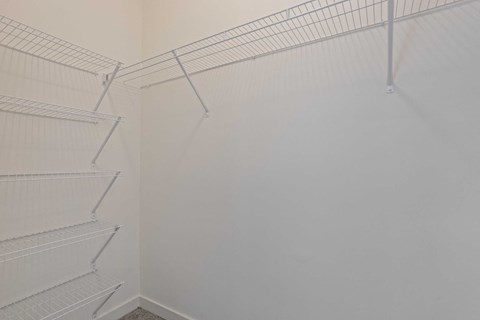 a walk in closet with white walls and empty shelves