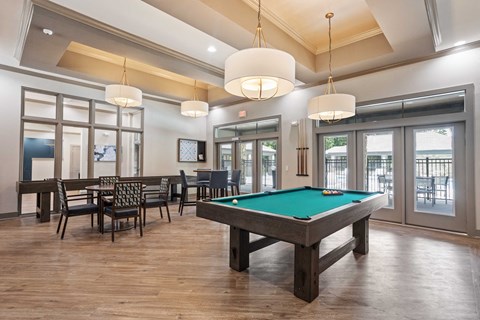 a pool table in a clubhouse with chairs and tables