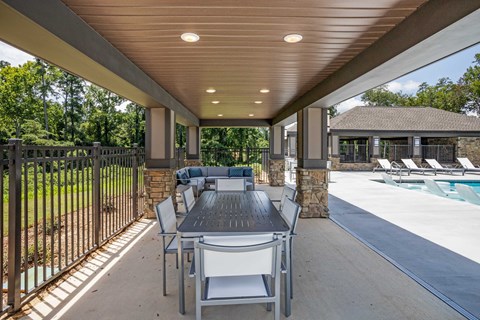 a patio with a dining table and chairs next to a pool