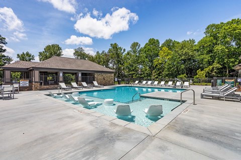 the resort style pool with lounge chairs and a building in the background